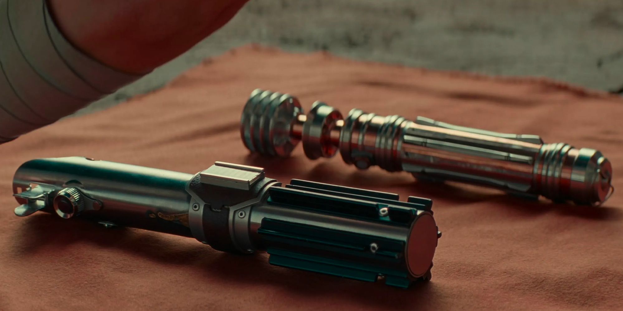 Luke and Anakin Skywalker's lightsabers laying on a cloth in The Rise of Skywalker as Rey is about to bury them on Tatooine