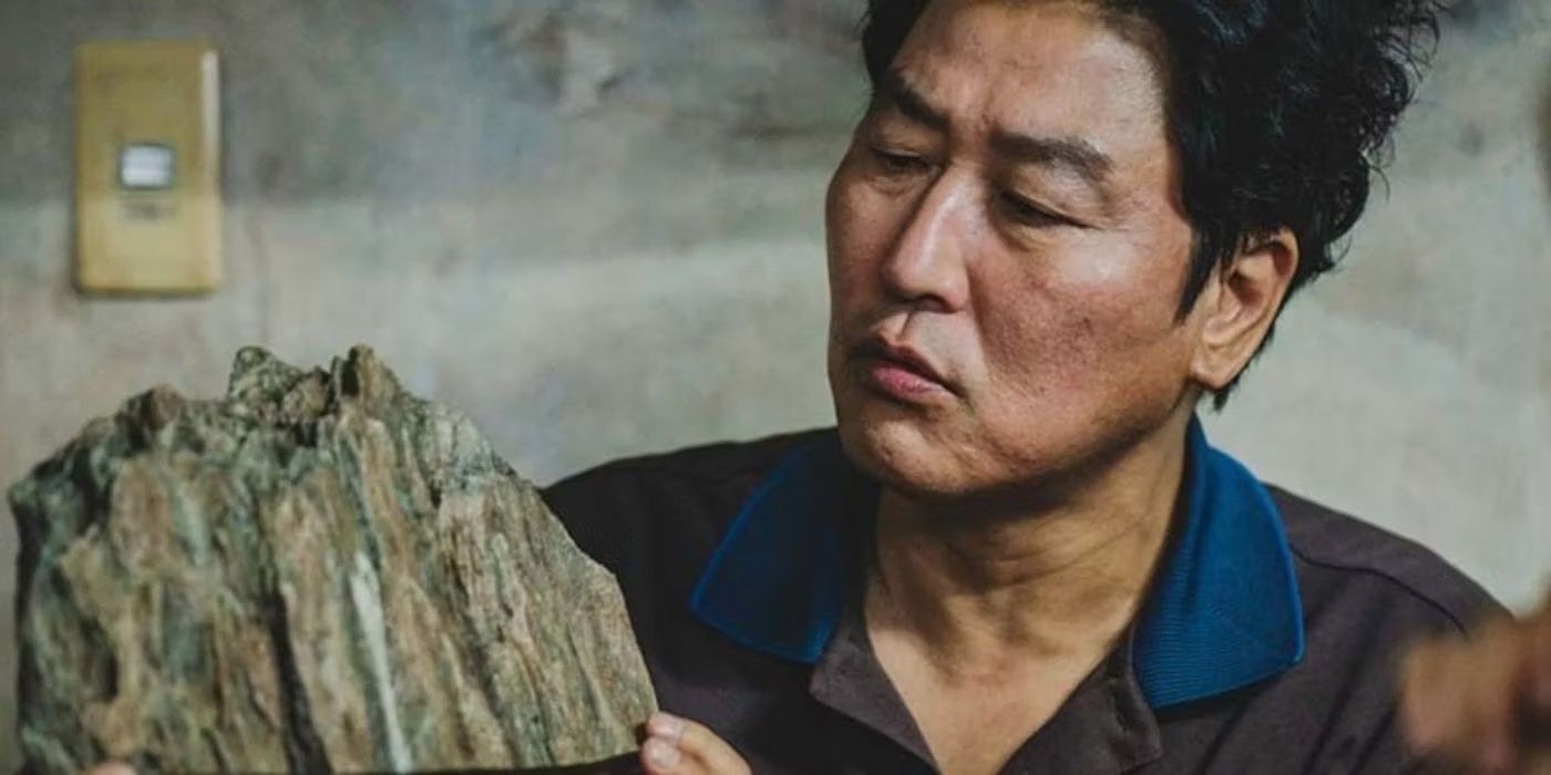 Song Kang-ho as Kim Ki-taek observes a strange rock object in a scene from Parasite.