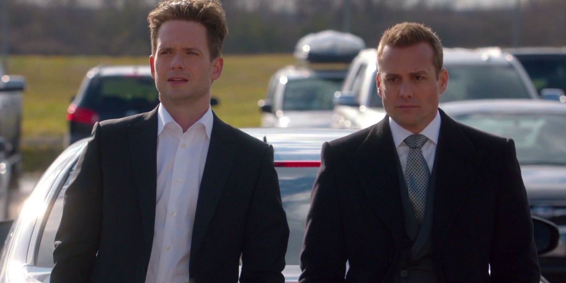 Mike Ross (Patrick J. Adams) and Harvey Specter (Gabriel Macht) sitting on the hood of a car in Suits.