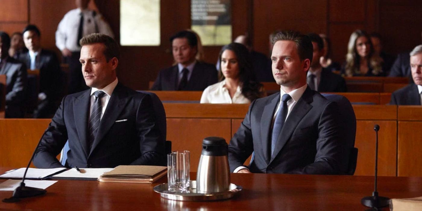 Harvey e Mike sentados atrás da mesa durante um julgamento na 5ª temporada de Suits, episódio 14, autodefesa