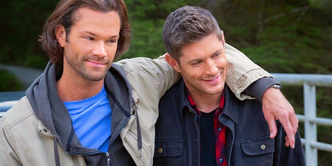 Jared Padelecki as Sam Winchester and Jensen Ackles as Dean Winchester smiling while standing in the forest in Supernatural's final episode