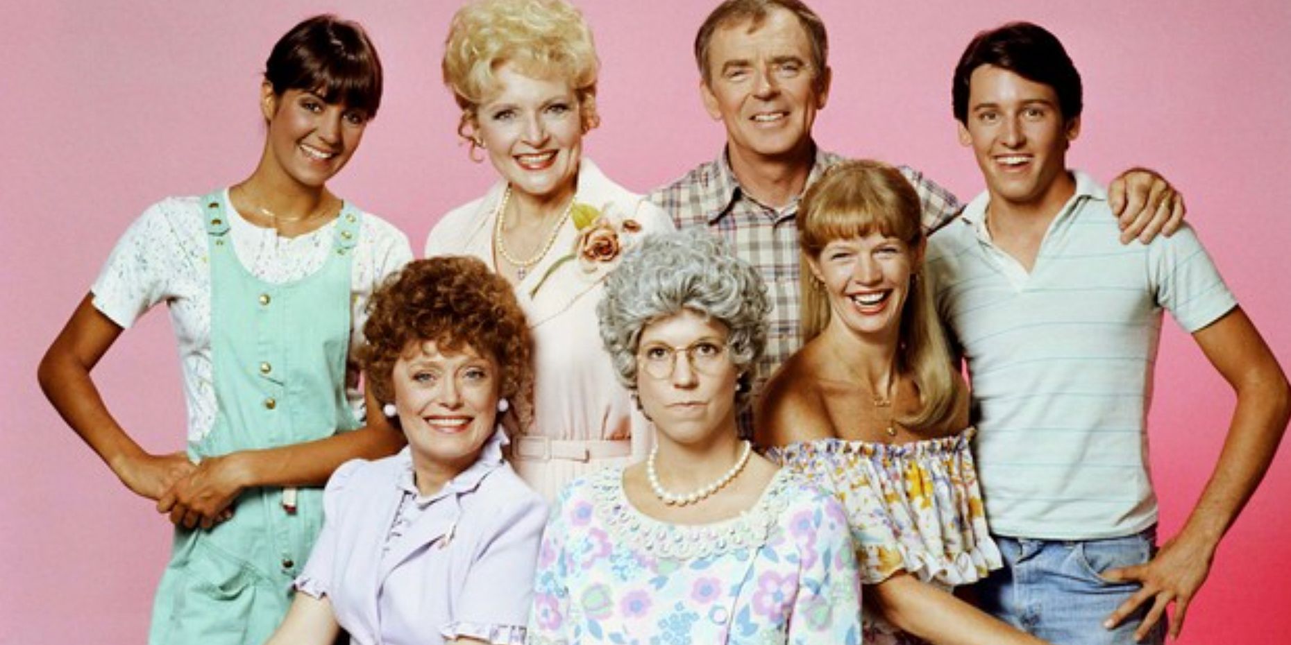 The original cast of Mamas Family poses together against a pink baground in a promotional family photo for the series
