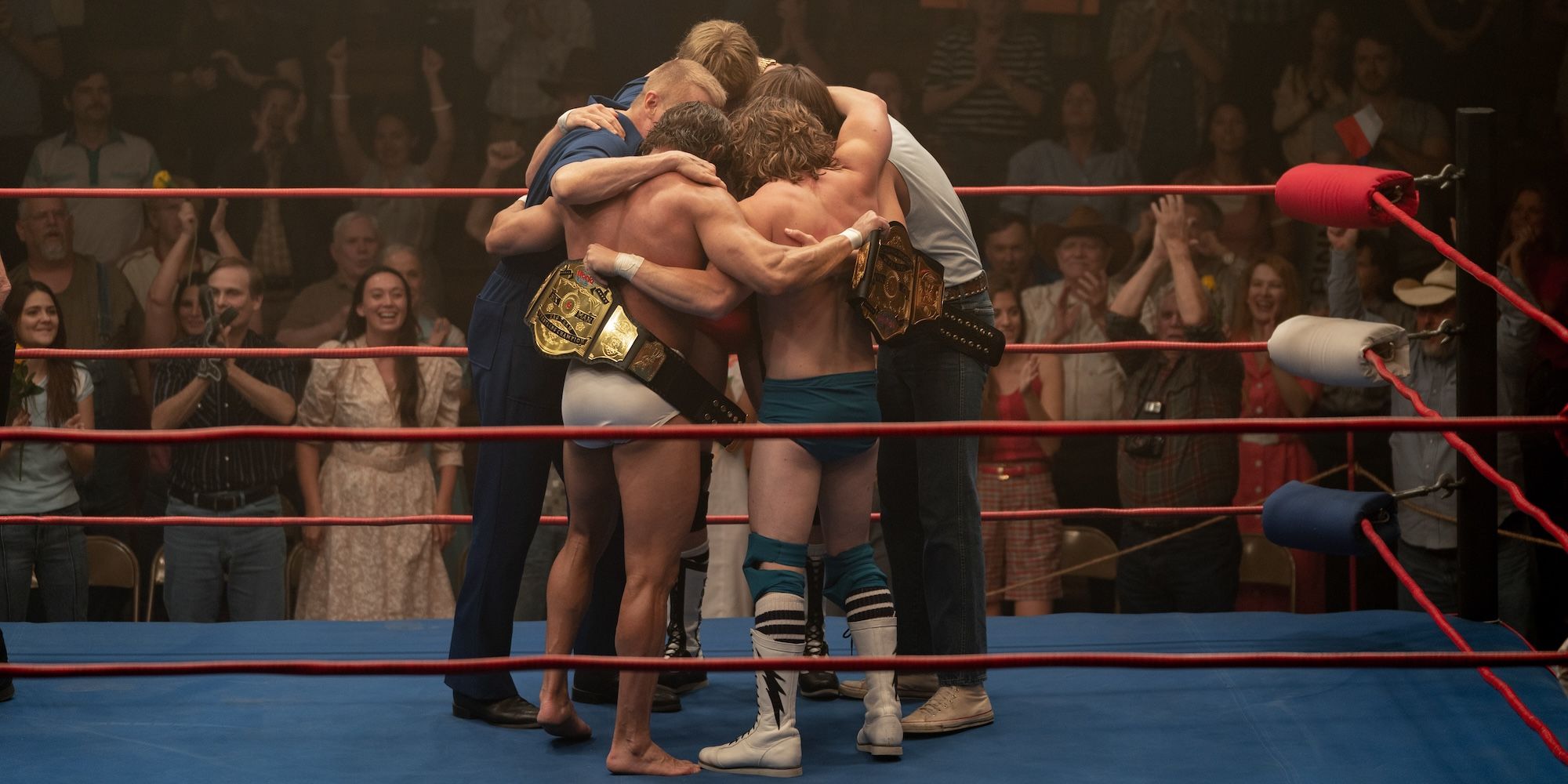 The Von Erich brothers and father hugging in a wrestling ring in The Iron Claw.