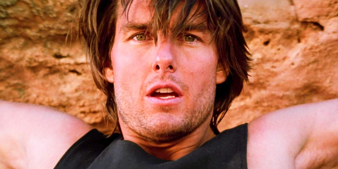 Tom Cruise holding onto a cliff as Ethan Hunt in Mission Impossible 2.