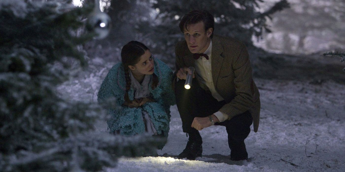 The Eleventh Doctor and Lily kneel in the snow with a torch in Doctor Who 2011 Christmas special