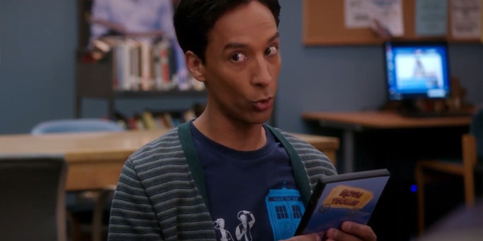Danny Pudi as Abed looking intrigued while holding a dvd in Community