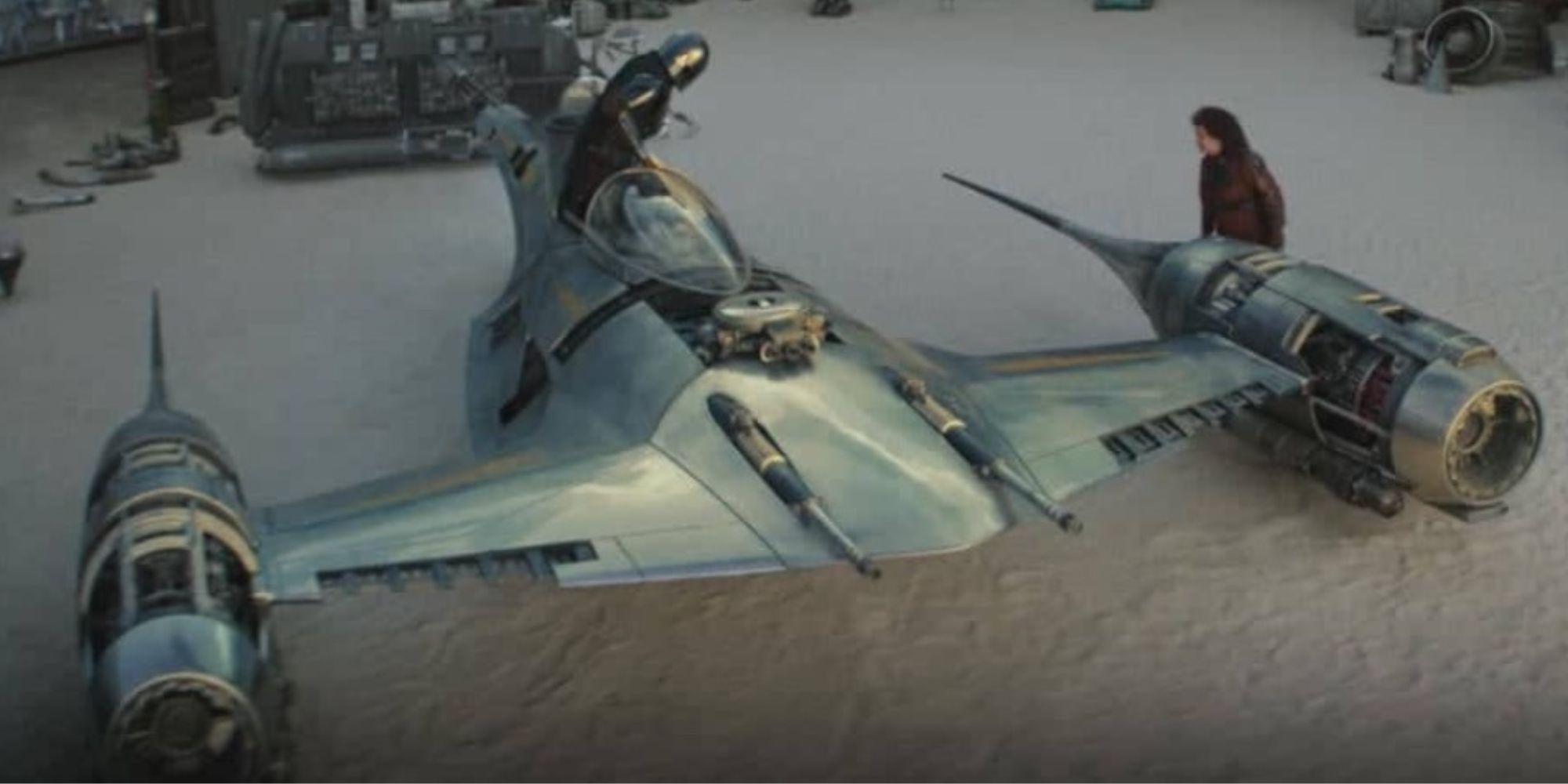 Din Djarin in the cockpit of his grounded Starfighter with Peli Motto standing by its left engine in The Mandalorian