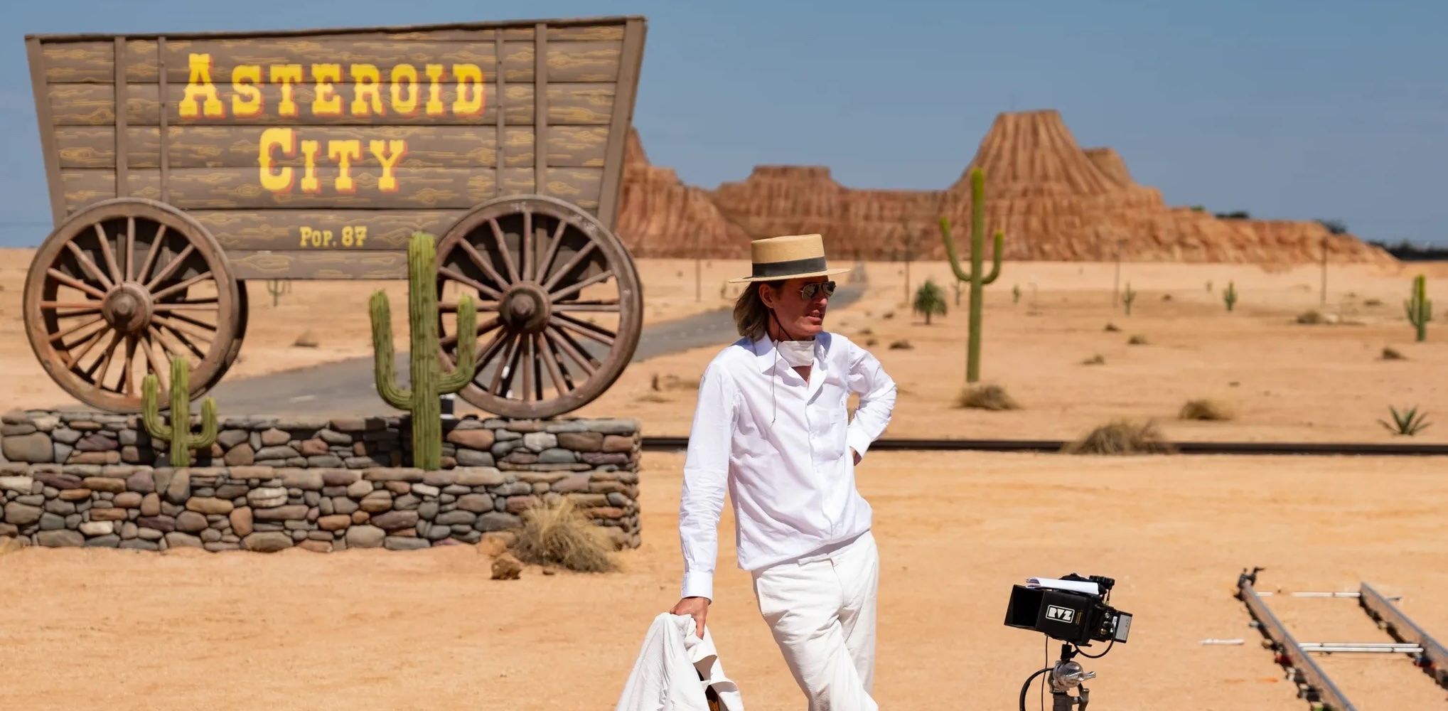 A photo of Wes Anderson in front of a wagon in the desert on the set of Asteroid City.