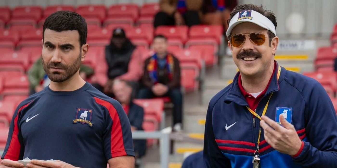 Brett Goldstein as Roy frowning next to Jason Sudeikis as Ted smiling in Ted Lasso