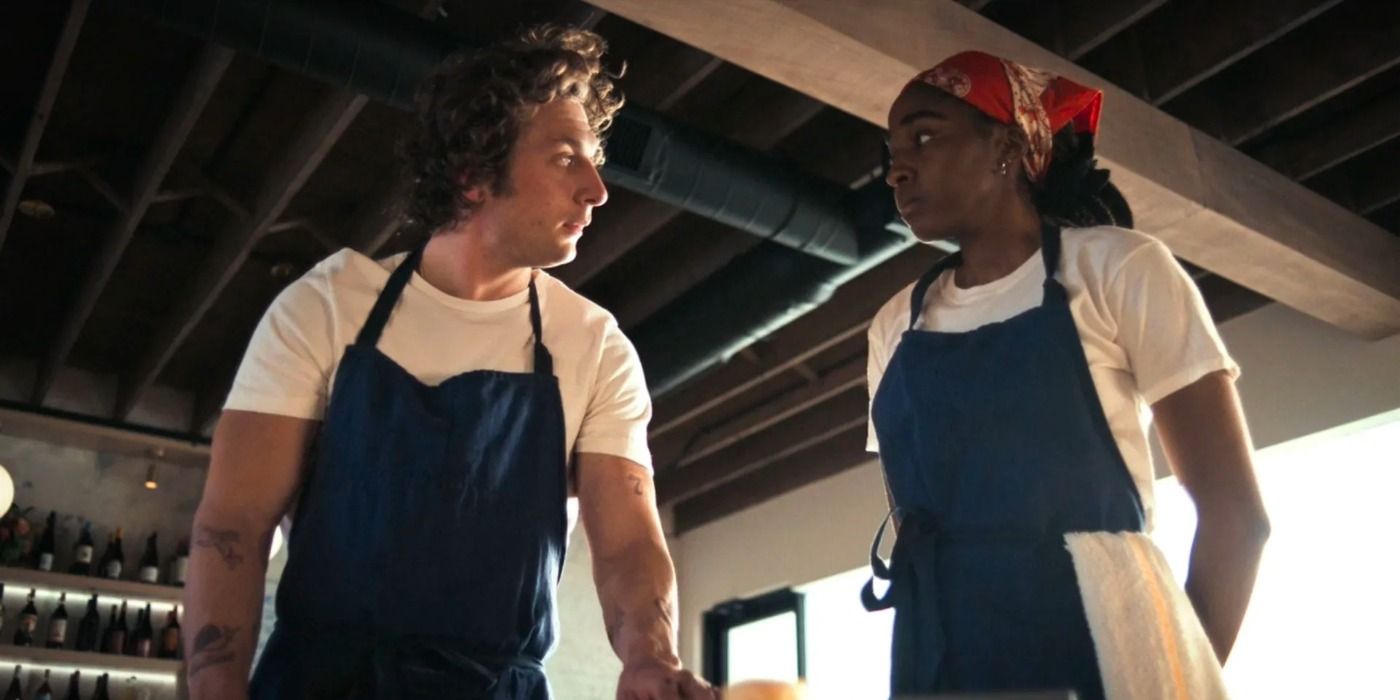 Carmy (Jeremy Allen White) e Sydney (Ayo Edibiri) se entreolham enquanto vestem seus uniformes de chef em The Bear.