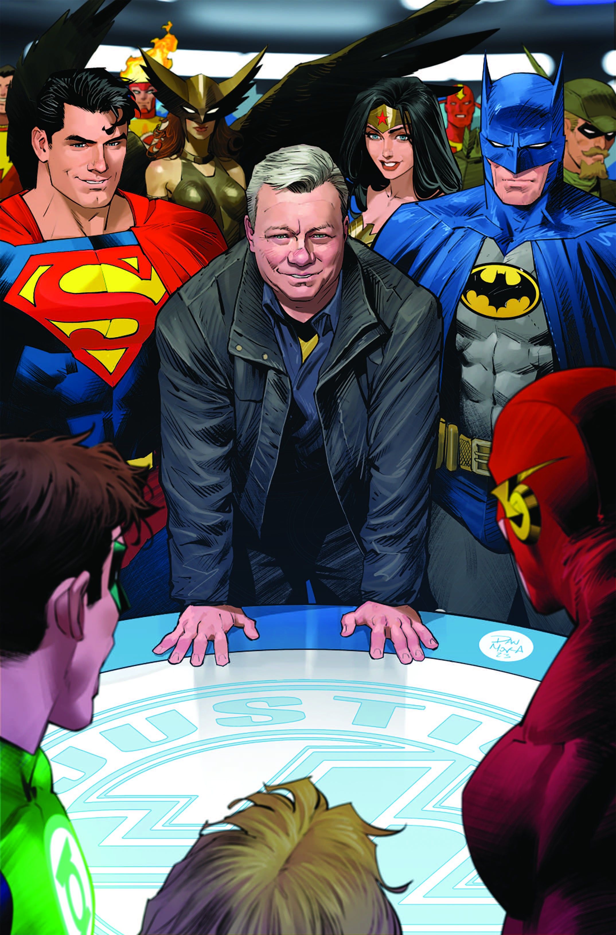 Image of William Shatner standing at the Justice League's meeting table, with members of the League, including Superman, Batman and Wonder Woman, standing around him.