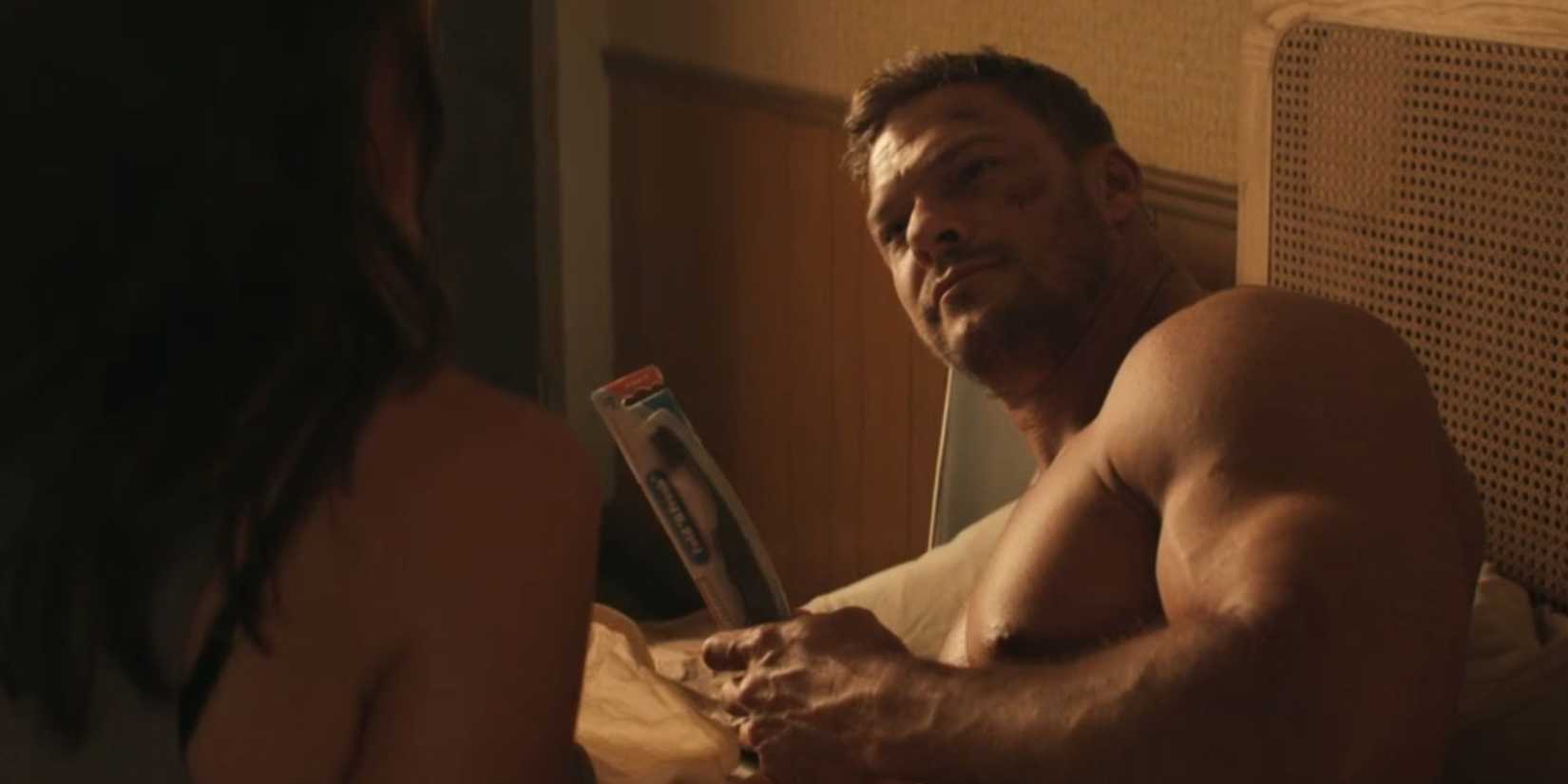 Alan Ritchson as Reacher in bed holding a toothbrush in Reacher