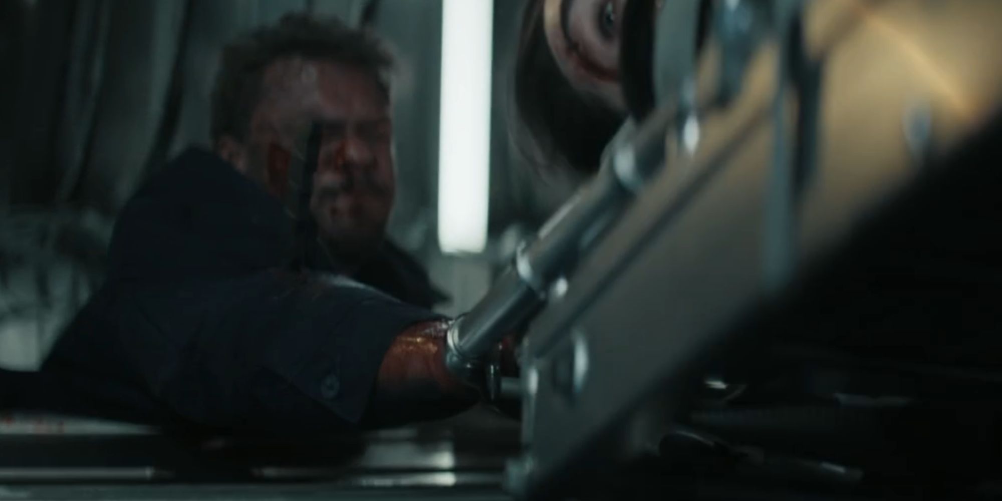 Alan Ritchson as Reacher looking strained as he holds onto Dixon's stretcher