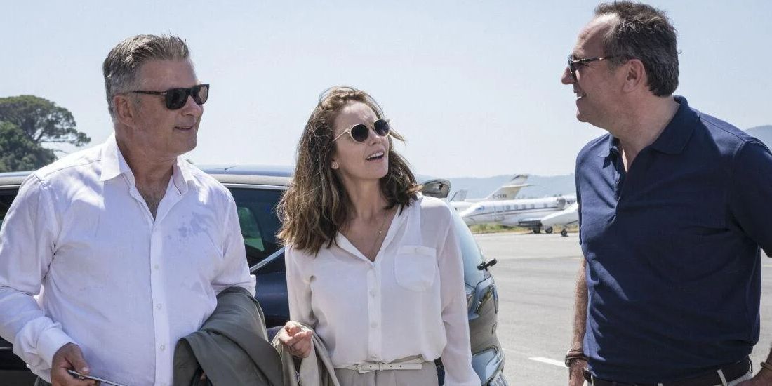 Alec Baldwin and Diane Lane smiling and talking to a man in a parking lot in Paris Can Wait