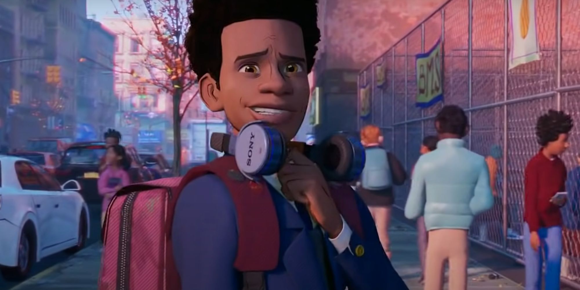 Miles Morales smiling with headphones round his neck as he walks down the street in Spider-Man: Into the Spider-Verse
