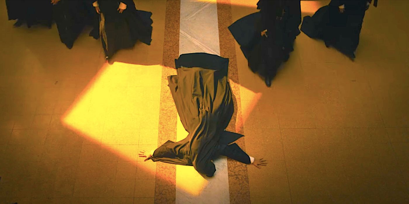A nun lies on the ground in the shape of a cross as others walk past her in The First Omen trailer.