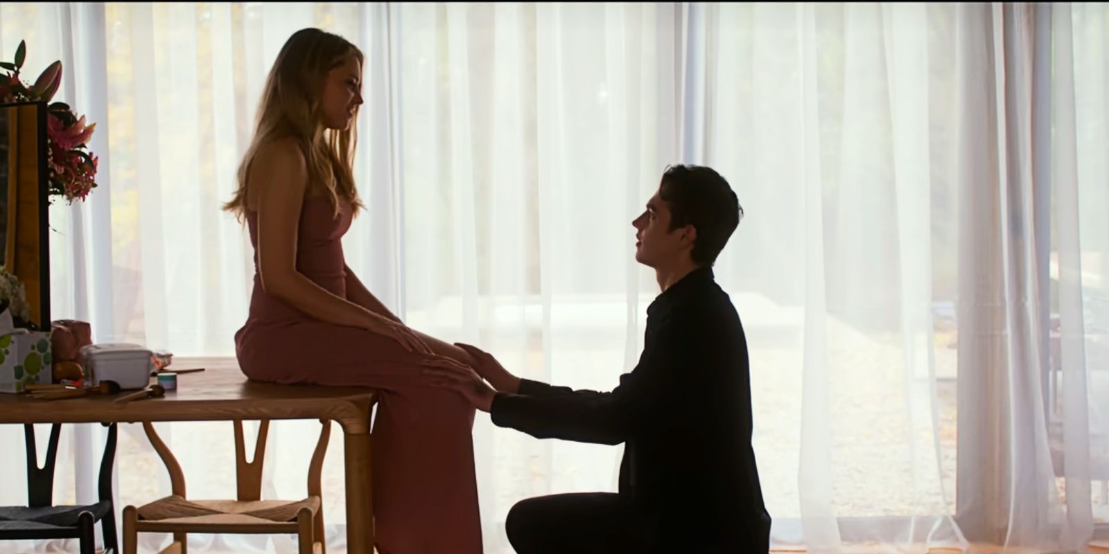 Tessa sits on a table while Hardin kneels down to propose in After Everything.