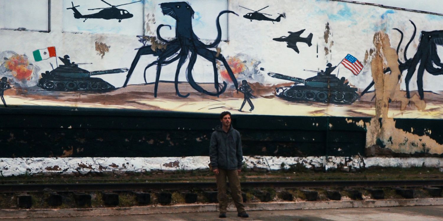 Andrew Kaulder (Scoot McNairy) standing under a mural depicting the mostly unseen aliens in Monsters