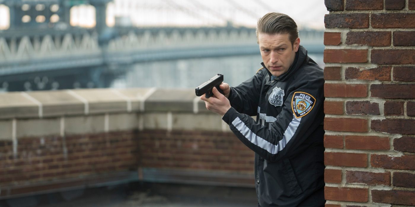 Carisi peeks around a corner with a gun in the SVU episode Intimidation Game