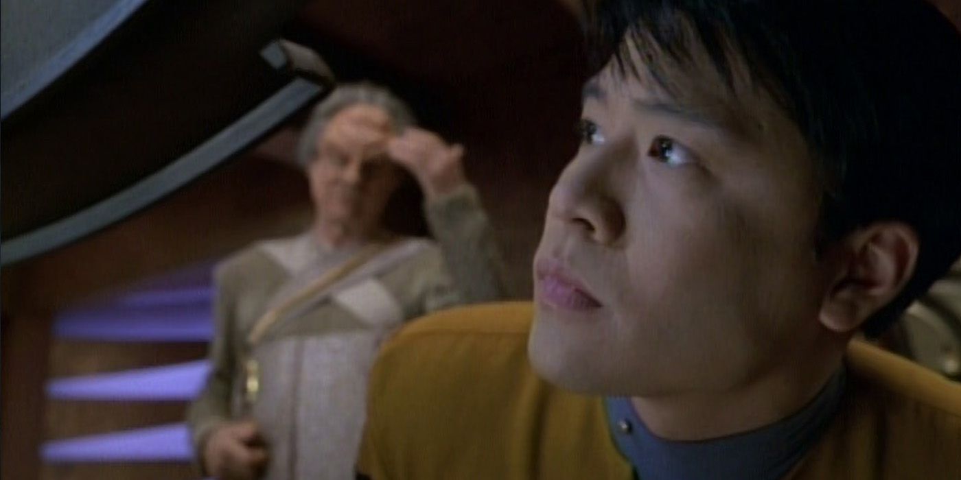 close up of harry kim looking up with an alien man in the background of voyager emanations