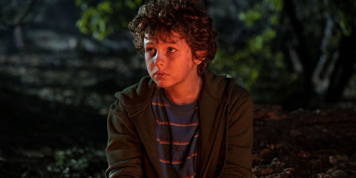 Connor (Finn Little) sits by a fire in Those Who Wish Me Dead