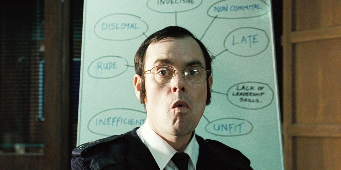 Hot Fuzz Tony in front of the whiteboard with unflattering descriptions pointing at him