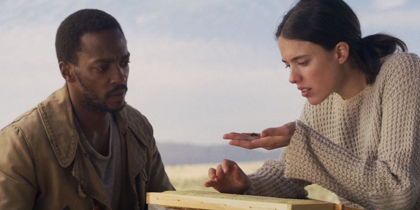 Anthony Mackie as Micah looking at an object in and Sam Walden's (Margaret Qualley) hand in Io
