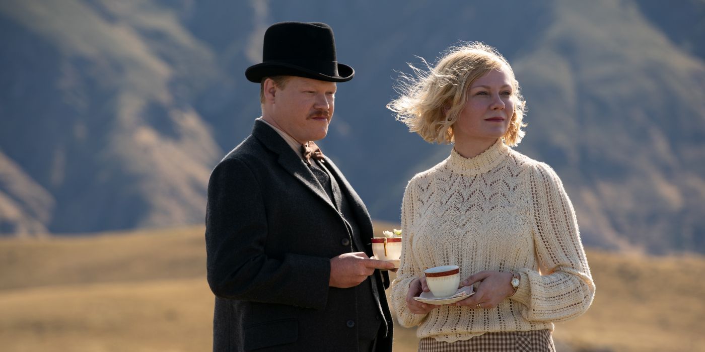 Jesse Plemons as George Burbank and Kirsten Dunst as Rose Gordon standing together in a field with mountains in the distance in The Power of the Dog.