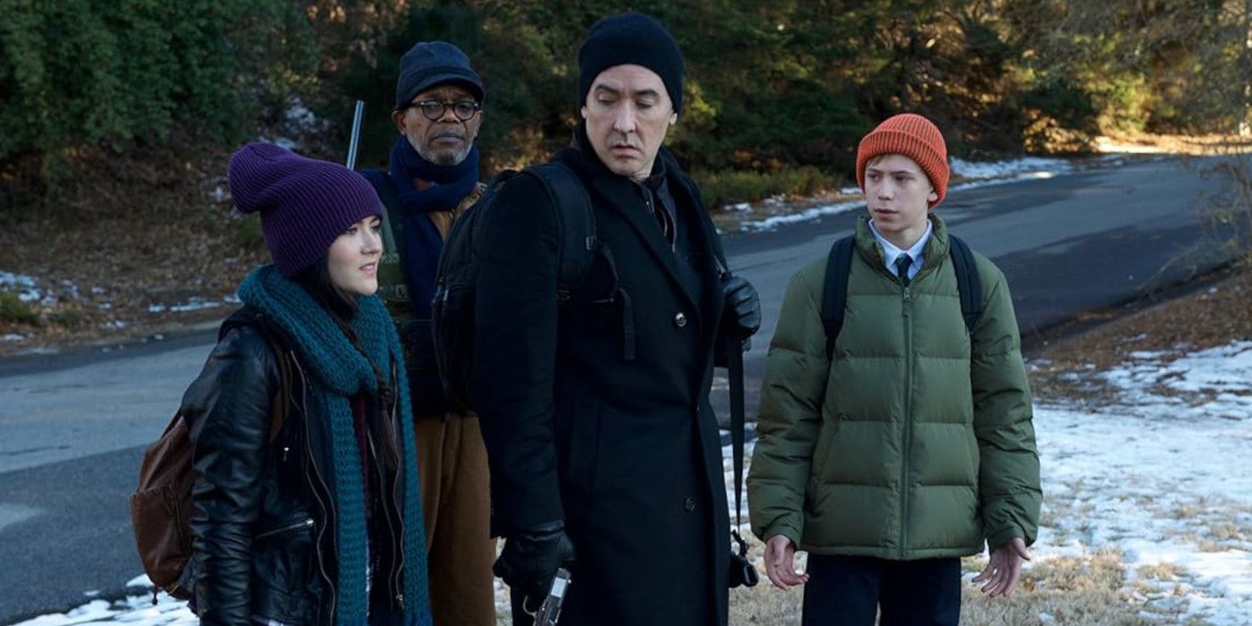 John Cusack and Samuel L. Jackson stand in a group of people by a snowy road in Cell