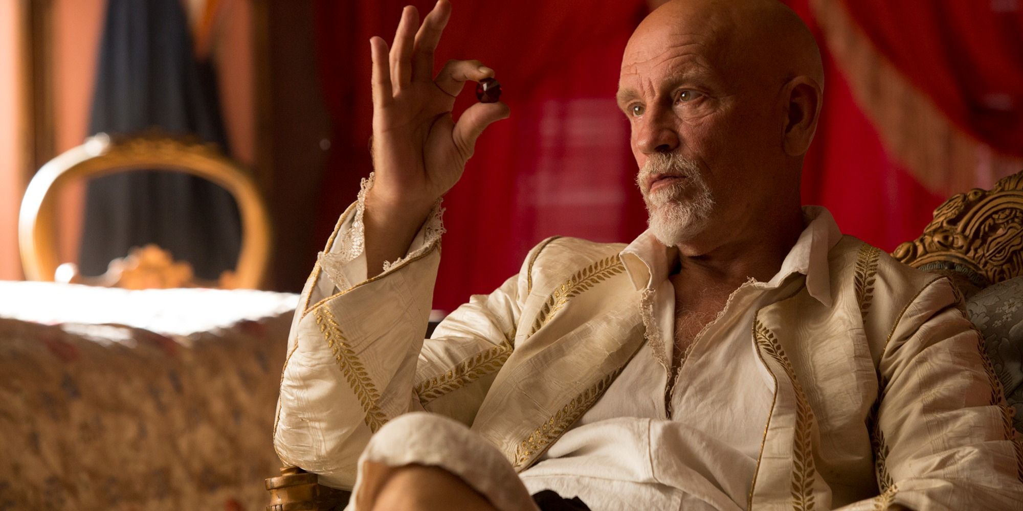 John Malkovich as Blackbeard holding a ball and sitting in a chair in Crossbones