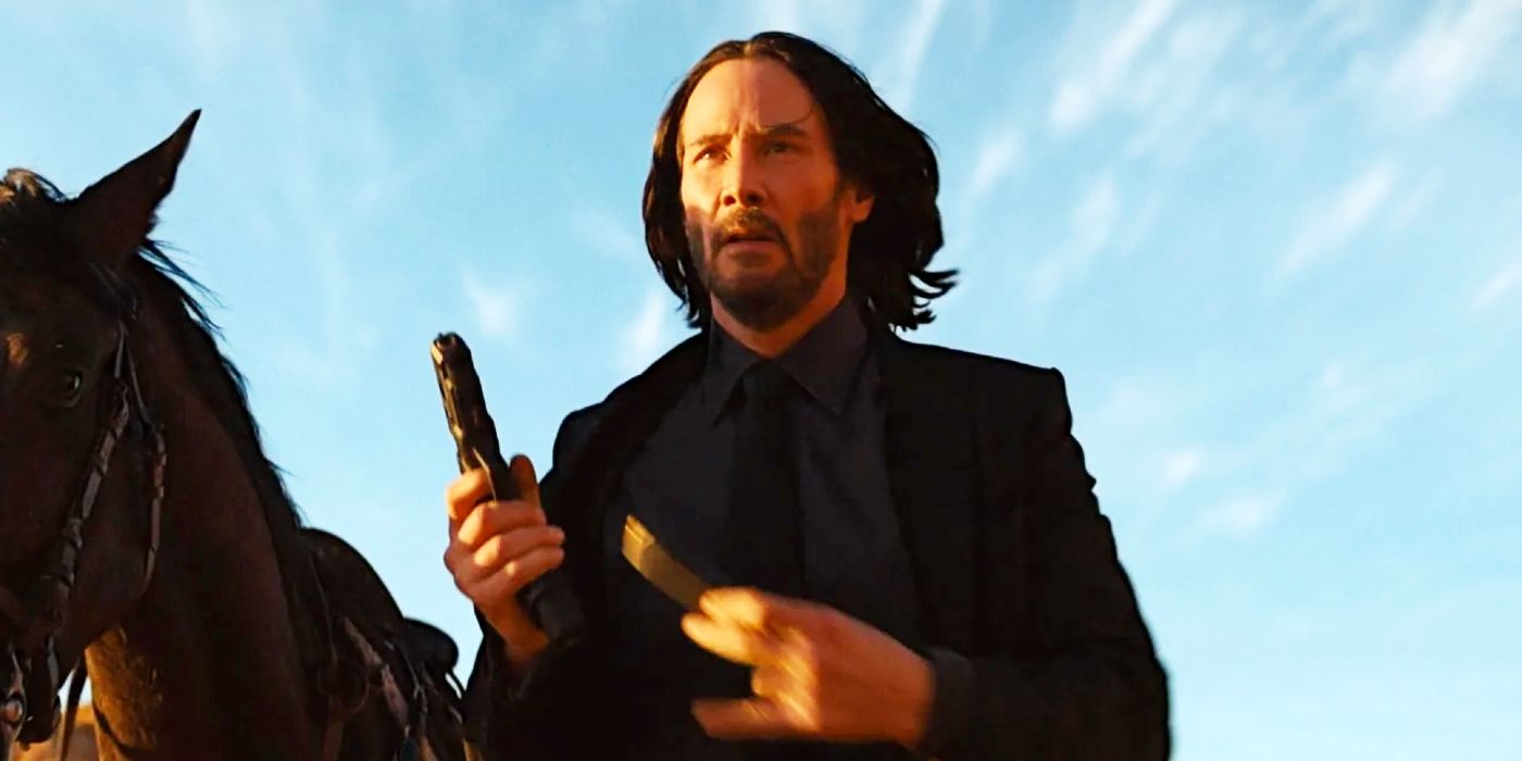 John Wick (Keanu Reeves) reloading a pistol next to a horse in John Wick: Chapter 4