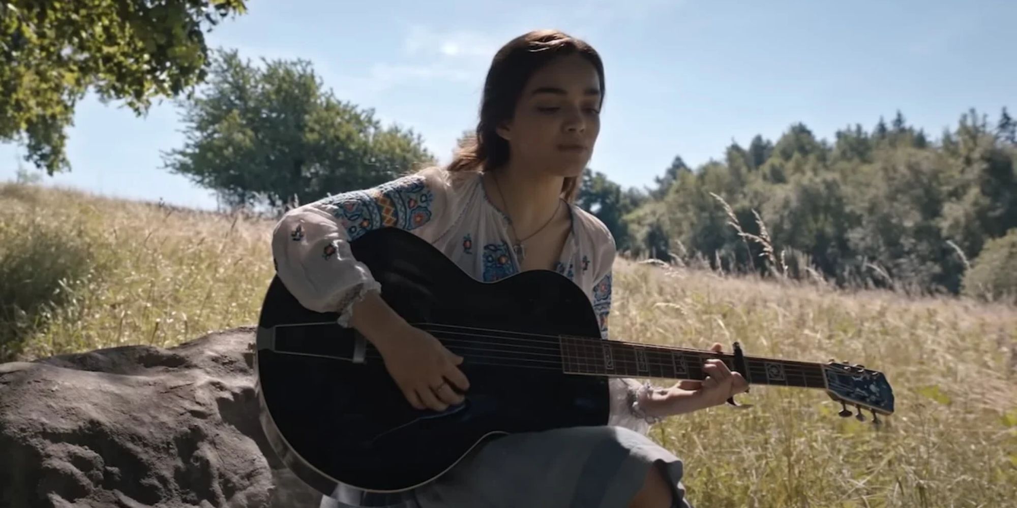 Lucy-Gray-Playing-Guitar-In-The-Meadow