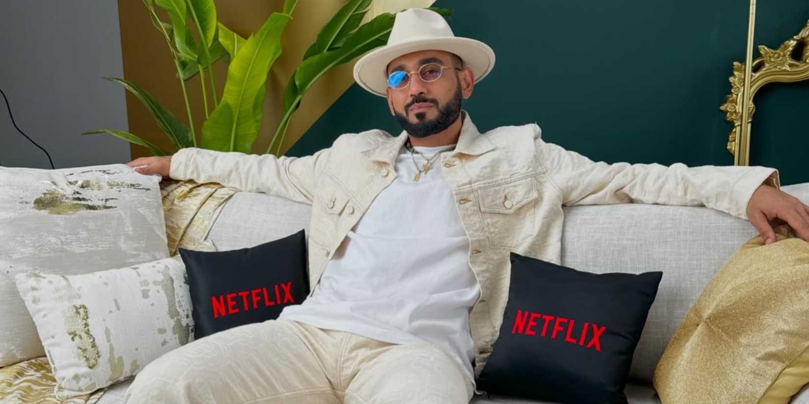 Dubai Bling DJ Bliss seated on a couch with black Netflix pillows next to him