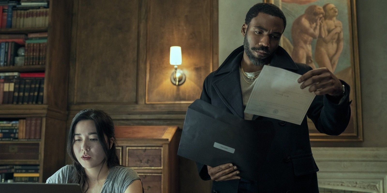 Donald Glover and Maya Erskine in an office looking at documents in Mr. & Mrs. Smith tv series
