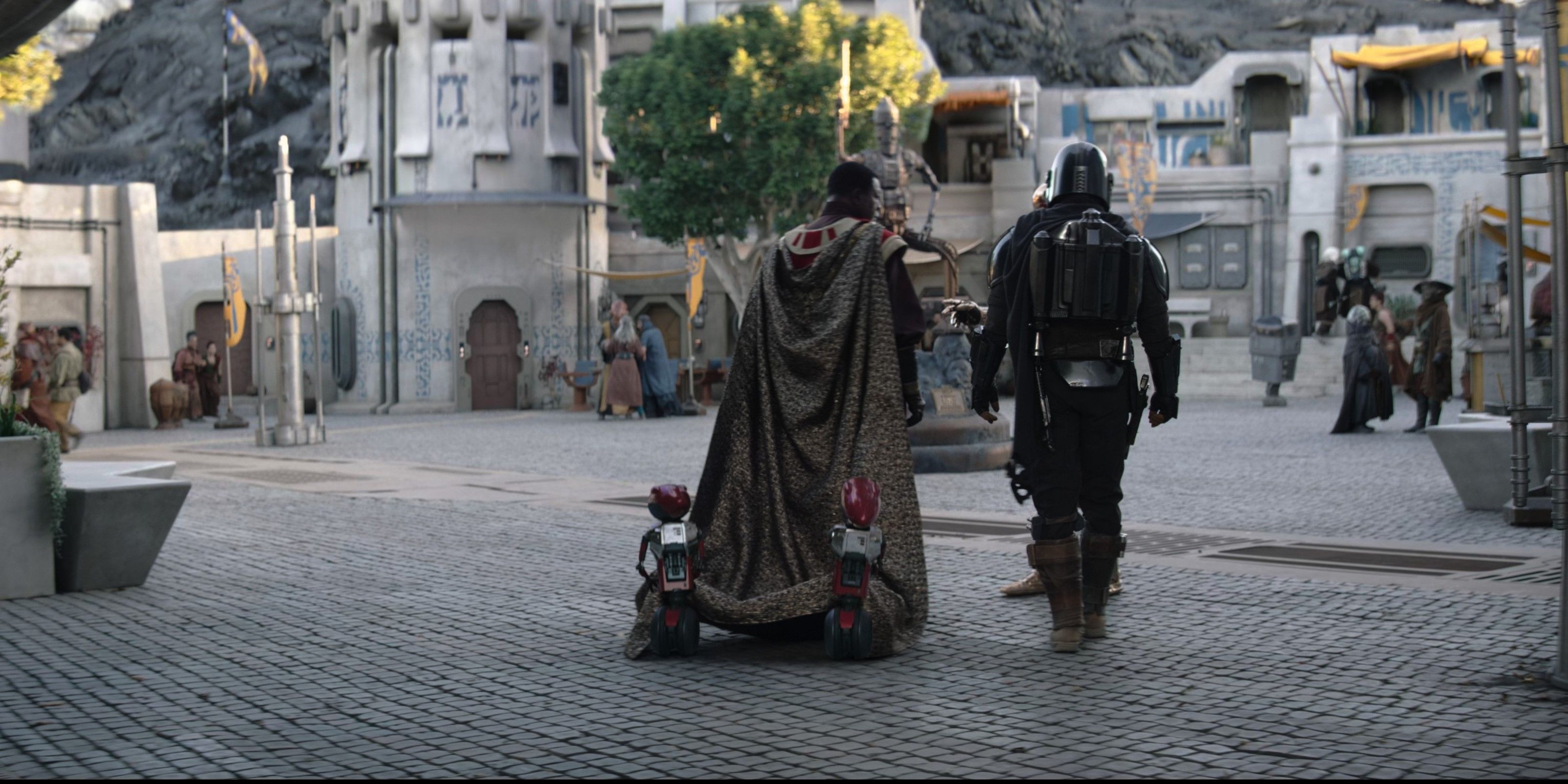 Greef Karga (Carl Weathers) e Din Djarin (Pedro Pascal) caminham pelas ruas de Nevarro no episódio 1 da 3ª temporada de The Mandalorian.