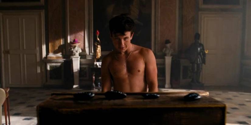 A shirtless Oliver (Barry Keoghan) looking at the Catton family's death stones at the end of Saltburn.
