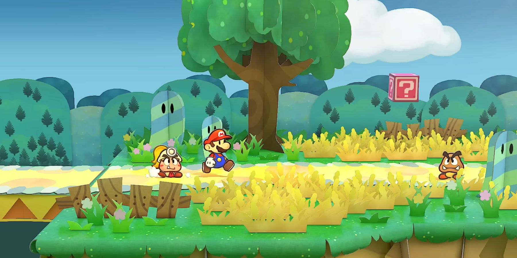 Mario, in an art style that makes him look like paper, traveling with Goombella, a female Goomba with a mining helmet on. The two are on a dirt road heading toward a hostile Goomba. There is a red question mark block floating in the air.