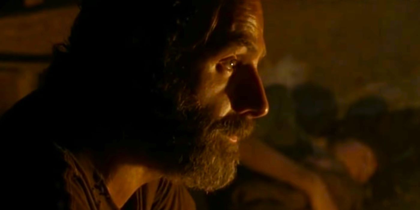 Rick Grimes in firelight with Carl sleeping in the background in The Walking Dead season 5 episode 10