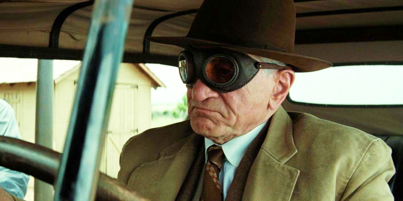 Robert de Niro wearing goggles behind the wheel of a car as William Hale in Killers of the Flower Moon