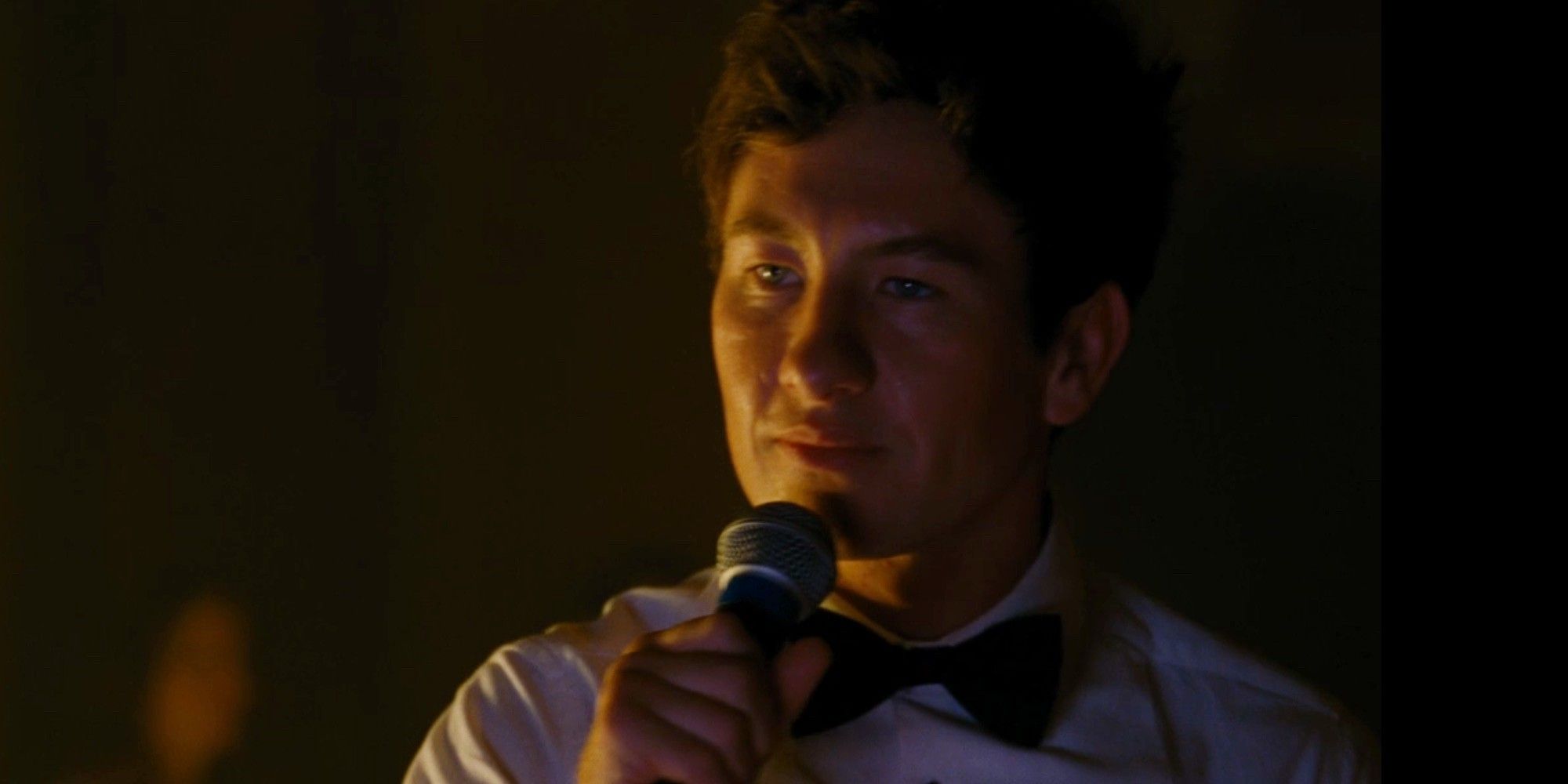 Oliver (Barry Keoghan) wearing a bowtie while singing karaoke in Saltburn.