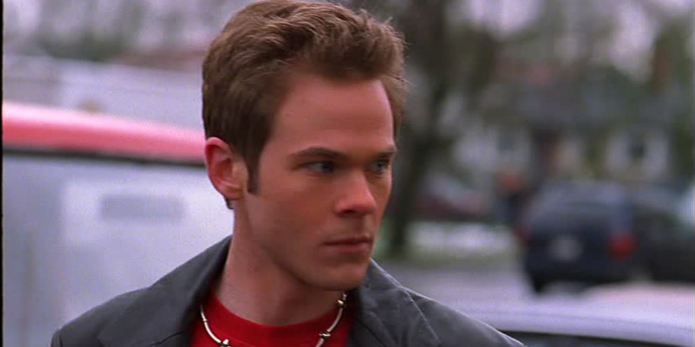 Shawn Ashmore como Eric Summers em Smallville parecendo zangado no estacionamento da escola.