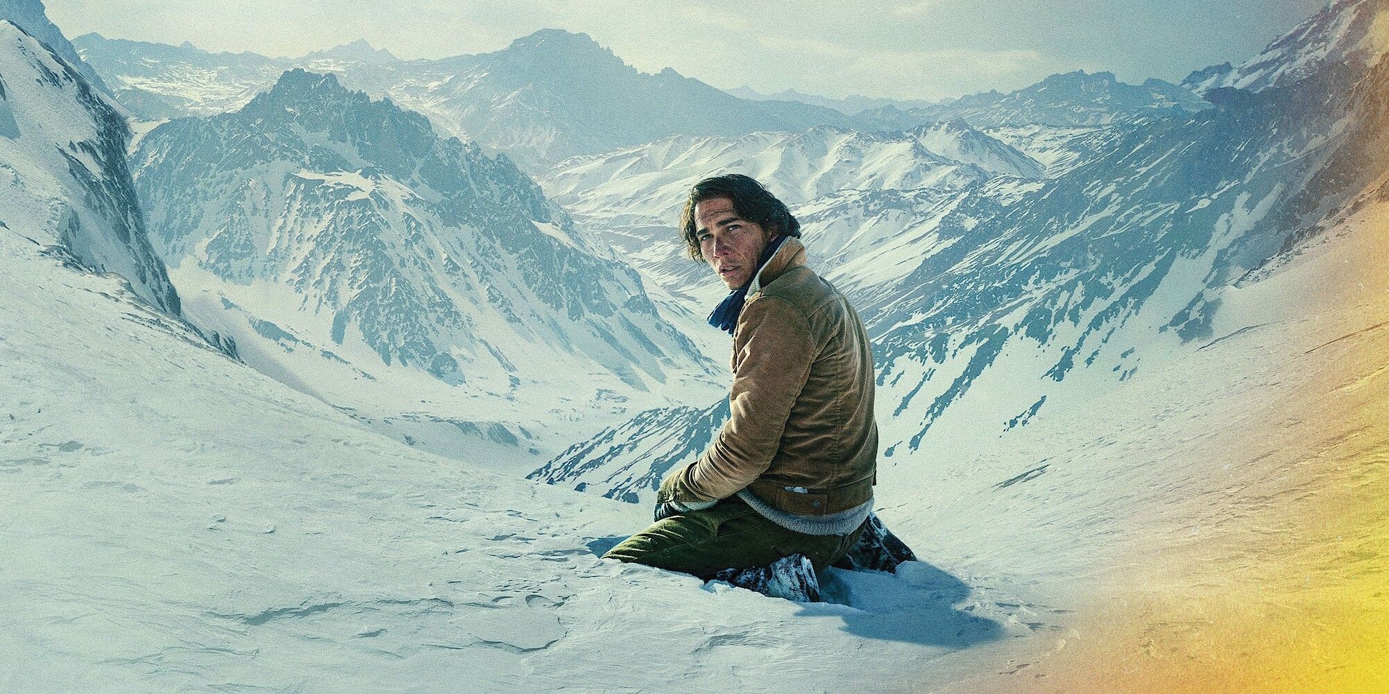 Enzo Vogrincic como Numa ajoelhado em uma montanha nevada em A Sociedade da Neve
