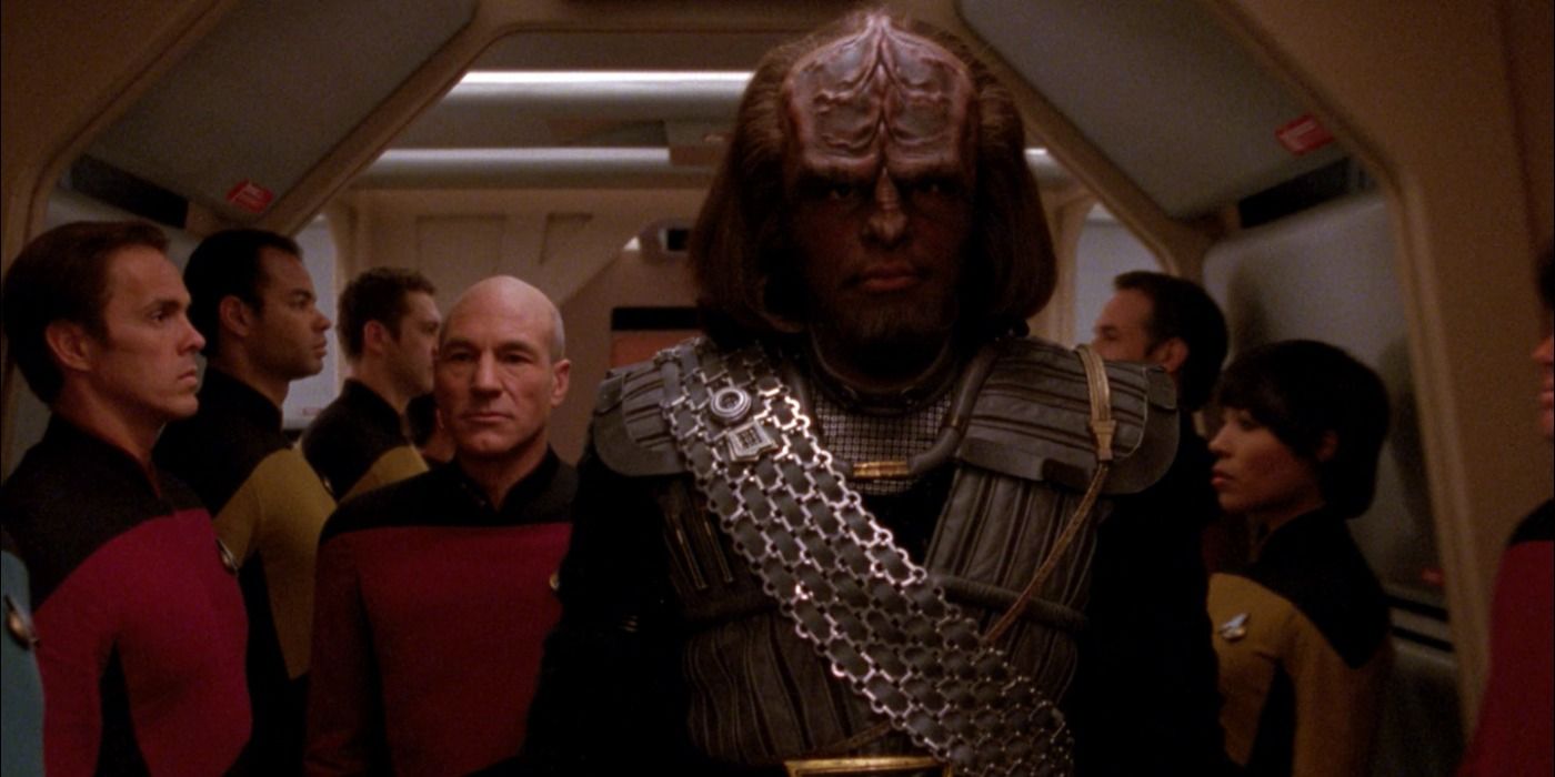 Image of Worf, in his Klingon gear, walking down the corridor of the Enterprise while other offices are standing by.