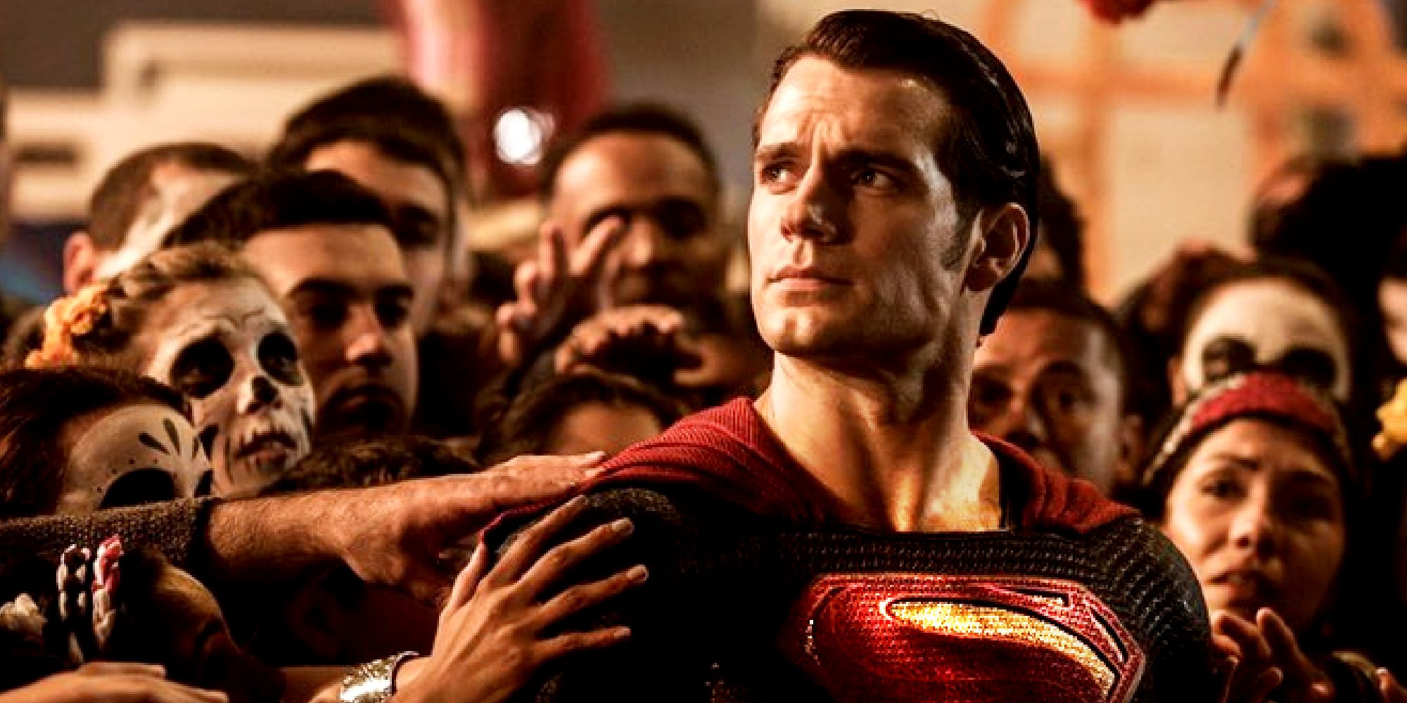 Henry Cavill looking upwards while being surrounded by a crowd in Batman v Superman Dawn of Justice