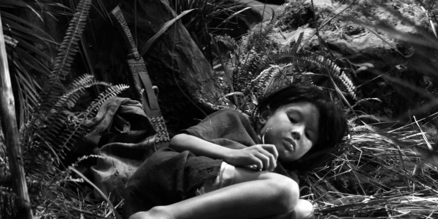 The boy (Mika Agilos) lying next to a bolo with intricate carvings on the jungle floor in Independencia by Raya Martin
