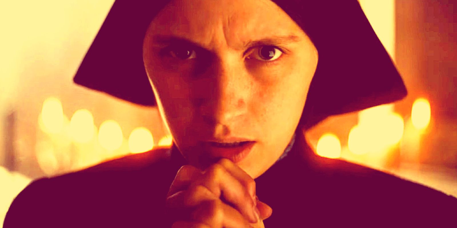 A nun clasps her hands together while praying in The First Omen.