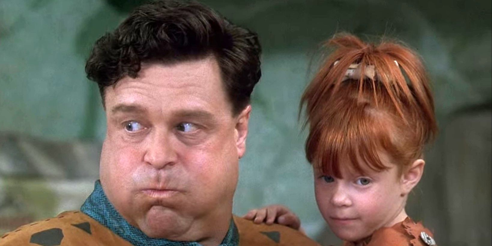 John Goodman as Fred Flintstone holding his daughter Pebbles in The Flintstones.
