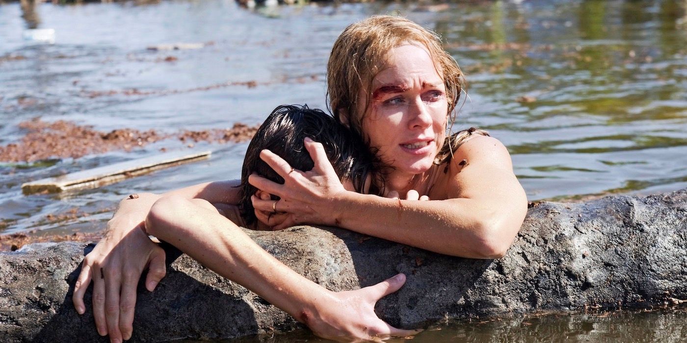 Naomi Watts and Tom Holland stuck in a flood, holding onto one another and onto a tree trunk 