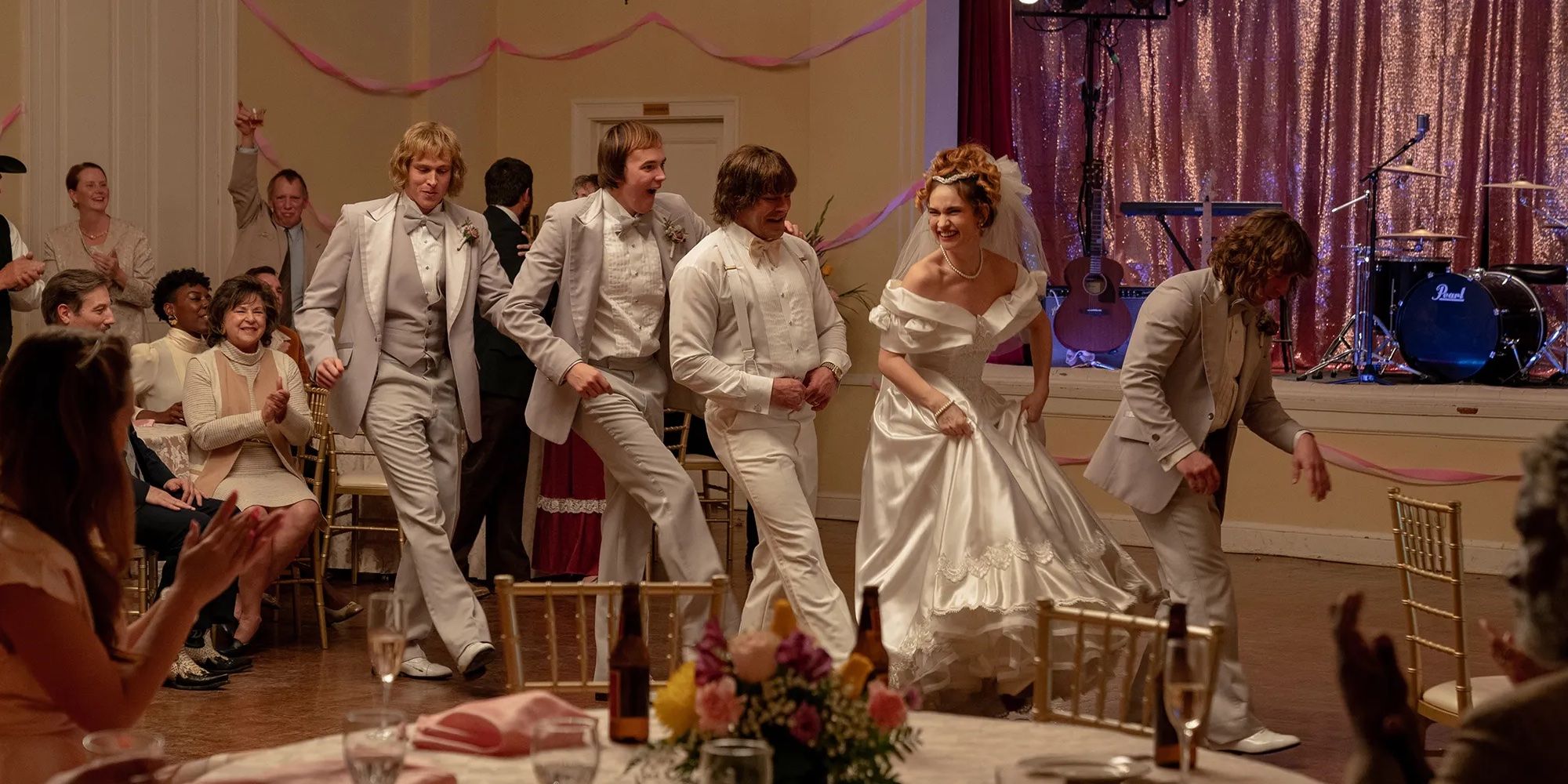 Pam (Lily James) and Kevin Von Erich (Zac Efron) dancing with his brothers at their wedding in The Iron Claw.