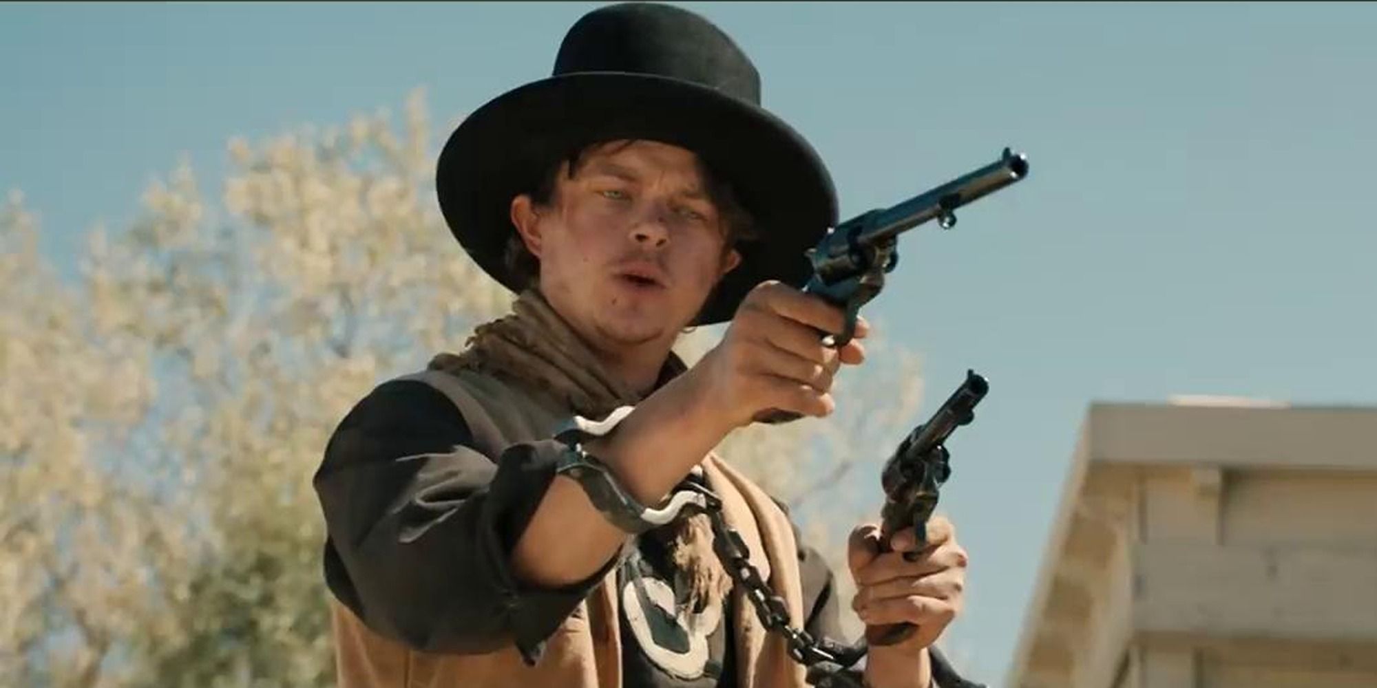 Dane DeHaan holding up guns as Billy the Kid in The Kid (2019_
